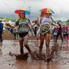 Festival goers splash through a muddy puddle at Worthy Farm in Somerset, on the third day of the Glastonbury music festival