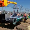 Mercedes Formula One driver Hamilton of Britain stands beside his car as it is being craned off the track during the first practice session of the Australian F1 Grand Prix in Melbourne