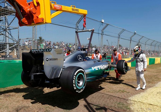 Mercedes Formula One driver Lewis Hamilton of Britain stands beside his car as it is being craned off the track during the first practice session of the Australian F1 Gra