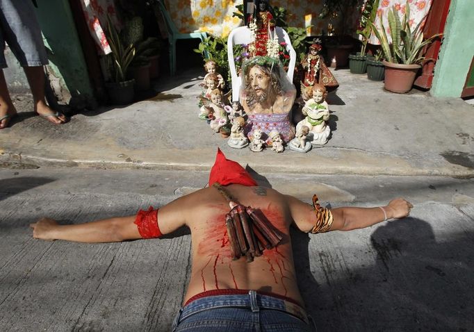 REFILE - ADDING ADDITIONAL CAPTION INFORMATION A hooded penitent with a bloodied back prays while lying on his belly in front of an image of Jesus Christ during Maundy Thursday Lenten rites in Mandaluyong city, metro Manila March 28, 2013. Maundy Thursday or Holy Thursday is the day Christians commemorate the Last Supper of Jesus Christ. Holy Week is celebrated in many Christian traditions during the week before Easter. REUTERS/Romeo Ranoco (PHILIPPINES - Tags: POLITICS RELIGION SOCIETY TPX IMAGES OF THE DAY) Published: Bře. 28, 2013, 5:57 dop.