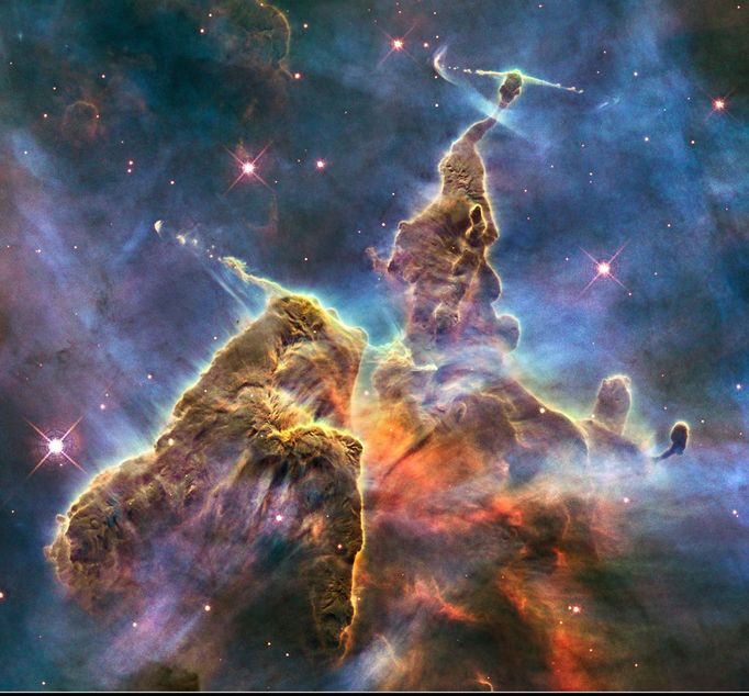 This brand new Hubble photo is of a small portion of one of the largest seen star-birth regions in the galaxy, the Carina Nebula. Towers of cool hydrogen laced with dust rise from the wall of the nebula. The scene is reminiscent of Hubble's classic "Pillars of Creation" photo from 1995, but is even more striking in appearance. The image captures the top of a three-light-year-tall pillar of gas and dust that is being eaten away by the brilliant light from nearby bright stars. The pillar is also being pushed apart from within, as infant stars buried inside it fire off jets of gas that can be seen streaming from towering peaks like arrows sailing through the air. Credit: NASA, ESA, and M. Livio and the Hubble 20th Anniversary Team (STScI)