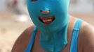 A woman, wearing a nylon mask, smiles as she rests on the shore during her visit to a beach in Qingdao, Shandong province July 6, 2012. The mask, which was invented by a woman about seven years ago, is used to block the sun's rays. The mask is under mass production and is on sale at local swimwear stores. REUTERS/Aly Song (CHINA - Tags: SOCIETY TRAVEL ENVIRONMENT) Published: Čec. 6, 2012, 4:26 odp.