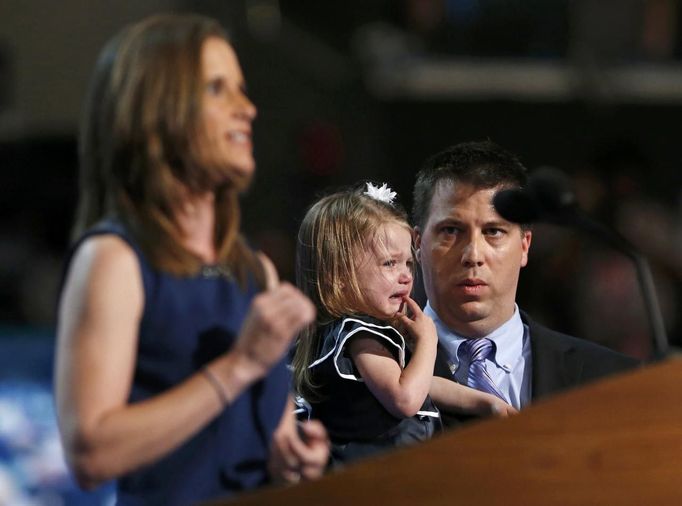 Stacey Lihn speaks about health care reform as her husband Caleb watches while holding their crying daughter Zoe during the first day of the Democratic National Convention in Charlotte, North Carolina, September 4, 2012. REUTERS/Eric Thayer (UNITED STATES - Tags: POLITICS ELECTIONS) Published: Zář. 5, 2012, 2:03 dop.