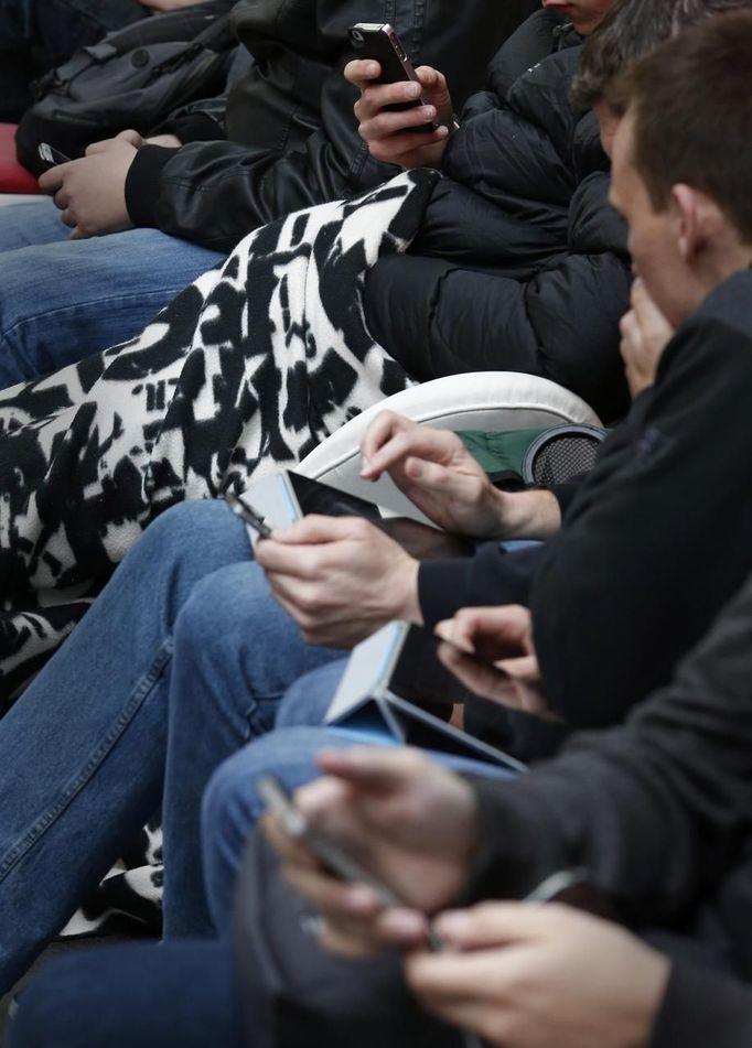 Shoppers waiting in a queue use mobile phones and tablets outside a telephone shop in central Sydney September 21, 2012, as they wait to buy the new Apple iPhone 5. Apple Inc's iPhone 5 hit stores around the globe on Friday, with fans snapping up the device that is expected to fuel a huge holiday quarter for the consumer giant. REUTERS/Tim Wimborne (AUSTRALIA - Tags: BUSINESS SCIENCE TECHNOLOGY TELECOMS) Published: Zář. 20, 2012, 11:39 odp.