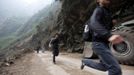 Men run past the debris of a landslide caused by Saturday's earthquake, on the side of a road to Lingguan township, in Baoxing county in Ya'an, Sichuan province April 22, 2013. Rescuers struggled to reach a remote, rural corner of southwestern China on Sunday as the toll of the dead and missing from the country's worst earthquake in three years climbed to 208 with almost 1,000 serious injuries. The 6.6 magnitude quake struck in Lushan county, near the city of Ya'an in the southwestern province of Sichuan, close to where a devastating 7.9 quake hit in May 2008, killing 70,000. REUTERS/Jason Lee (CHINA - Tags: DISASTER ENVIRONMENT) Published: Dub. 22, 2013, 12:12 odp.