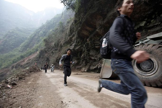 Men run past the debris of a landslide caused by Saturday's earthquake, on the side of a road to Lingguan township, in Baoxing county in Ya'an, Sichuan province April 22, 2013. Rescuers struggled to reach a remote, rural corner of southwestern China on Sunday as the toll of the dead and missing from the country's worst earthquake in three years climbed to 208 with almost 1,000 serious injuries. The 6.6 magnitude quake struck in Lushan county, near the city of Ya'an in the southwestern province of Sichuan, close to where a devastating 7.9 quake hit in May 2008, killing 70,000. REUTERS/Jason Lee (CHINA - Tags: DISASTER ENVIRONMENT) Published: Dub. 22, 2013, 12:12 odp.