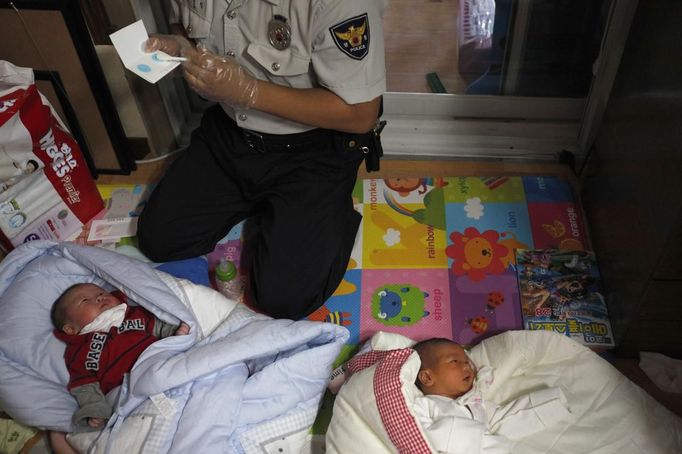 A police officer collects DNA samples from two abandoned babies after the babies were left at a "baby box" at Joosarang church in Seoul September 20, 2012. A South Korean pastor of the church who runs a "baby box" where mothers can leave unwanted infants has seen a sharp increase in the number of newborns being left there because, the pastor says, of a new law aimed protecting the rights of children. South Korea is trying to shed a reputation of being a source of babies for adoption by people abroad. It is encouraging domestic adoption and tightening up the process of a child's transfer from birth mother to adoptive parents. Picture taken September 20, 2012. REUTERS/Kim Hong-Ji (SOUTH KOREA - Tags: SOCIETY TPX IMAGES OF THE DAY) Published: Říj. 7, 2012, 7:31 dop.