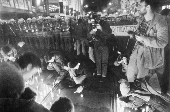Studenti na Národní třídě zapalují svíčky před policejním kordonem.