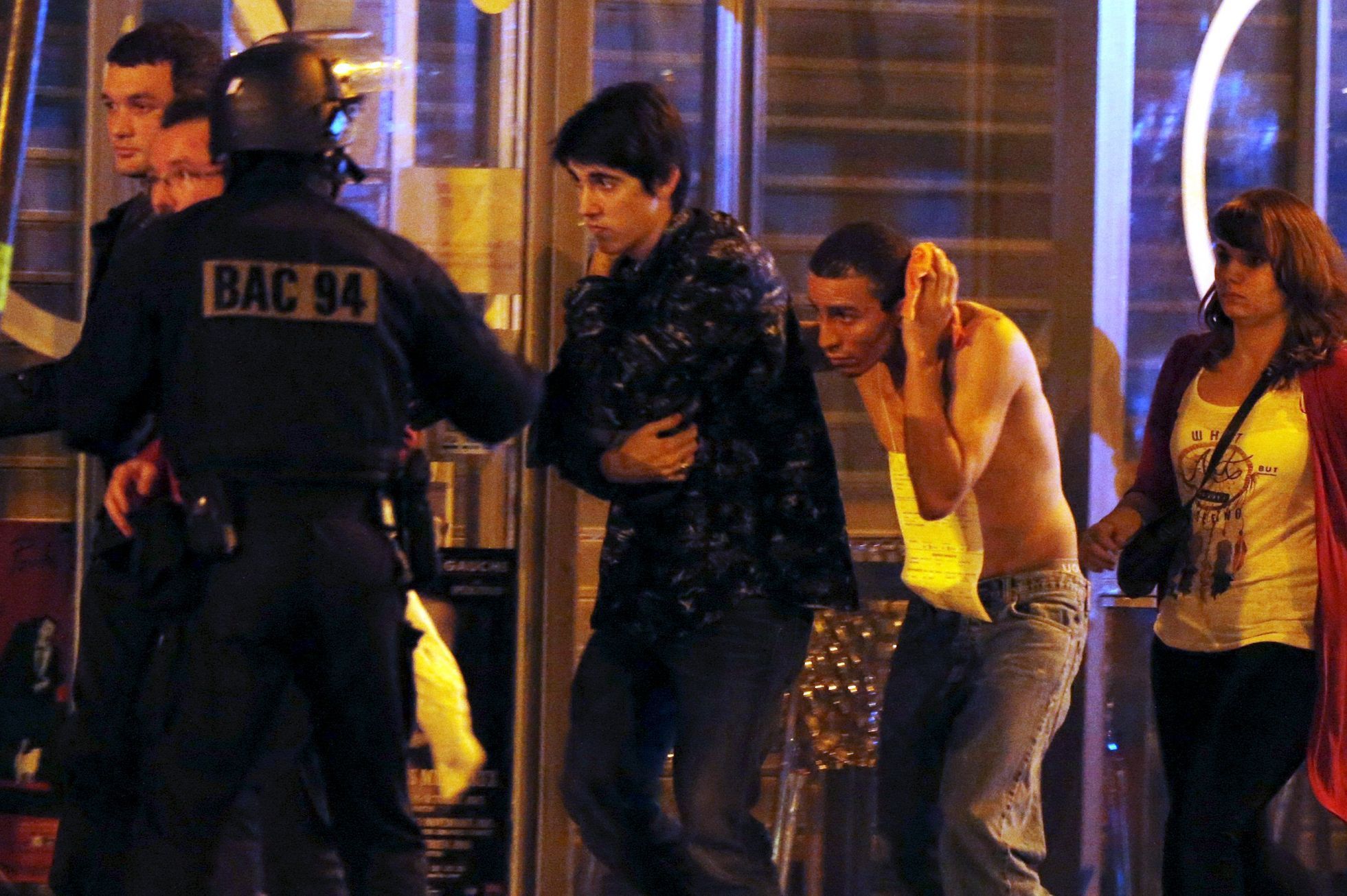 French special forces evacuate people, including an injured man holding his head, as people gather near the Bataclan concert hall following fatal shootings in Paris, France