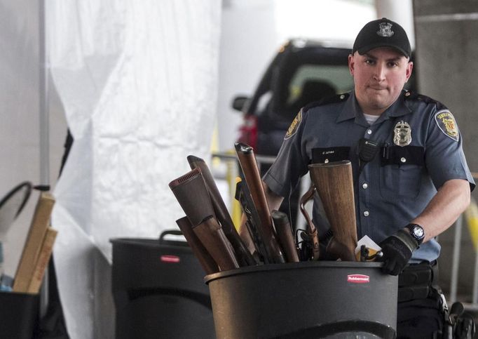 Seattle Police Officer Leyba carries a trash can full of guns during the gun buyback event in Seattle, Washington January 26, 2013. Participants received up to a $100 gift card in exchange for working handguns, shotguns and rifles, and up to a $200 gift card for assault weapons. The event lasted from 9 a.m. until shortly after noon, after the event ran out of $80,000 worth of gift cards. REUTERS/Nick Adams (UNITED STATES - Tags: POLITICS CIVIL UNREST) Published: Led. 27, 2013, 12:47 dop.