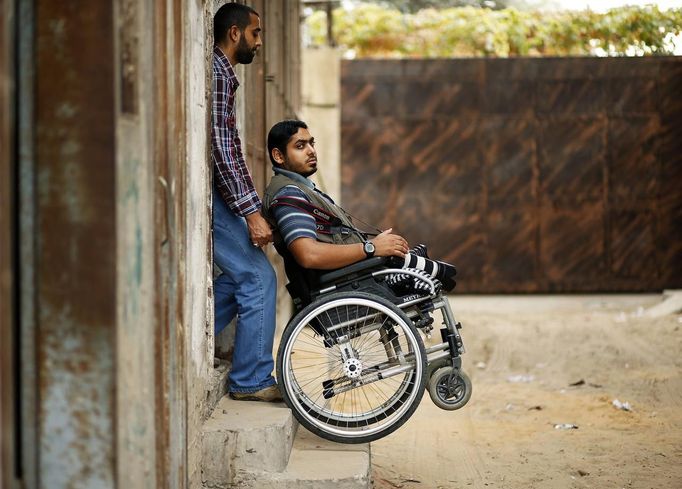 Wheelchair-bound Palestinian freelance photographer Moamen Qreiqea is helped by his brother at his home in Gaza City October 1, 2012. Qreiqea, 25, lost both his legs in an Israeli air strike in 2008 while taking pictures east of Gaza. The father of two is determined to continue his career despite his disability. REUTERS/Suhaib Salem (GAZA - Tags: MEDIA SOCIETY TPX IMAGES OF THE DAY) Published: Říj. 1, 2012, 3:39 odp.