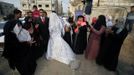 Relatives of Palestinian groom Emad al-Malalha, 21, celebrate as he stands next to Manal Abu Shanar, 17, his Egyptian bride upon the couple's arrival from a smuggling tunnel near the Gaza-Egypt border in the southern Gaza Strip March 21, 2013. Al-Malaha, who said that his bride was not given a permit from Egyptian authorities to enter the Gaza Strip, brought her from neighboring Egypt through a smuggling tunnel to celebrate his wedding in his native Gaza Strip. REUTERS/Ibraheem Abu Mustafa (GAZA - Tags: POLITICS SOCIETY TPX IMAGES OF THE DAY) Published: Bře. 21, 2013, 6:36 odp.