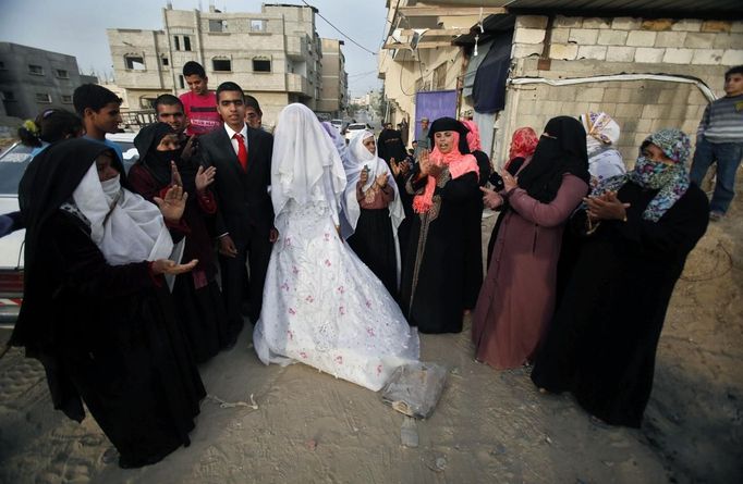 Relatives of Palestinian groom Emad al-Malalha, 21, celebrate as he stands next to Manal Abu Shanar, 17, his Egyptian bride upon the couple's arrival from a smuggling tunnel near the Gaza-Egypt border in the southern Gaza Strip March 21, 2013. Al-Malaha, who said that his bride was not given a permit from Egyptian authorities to enter the Gaza Strip, brought her from neighboring Egypt through a smuggling tunnel to celebrate his wedding in his native Gaza Strip. REUTERS/Ibraheem Abu Mustafa (GAZA - Tags: POLITICS SOCIETY TPX IMAGES OF THE DAY) Published: Bře. 21, 2013, 6:36 odp.