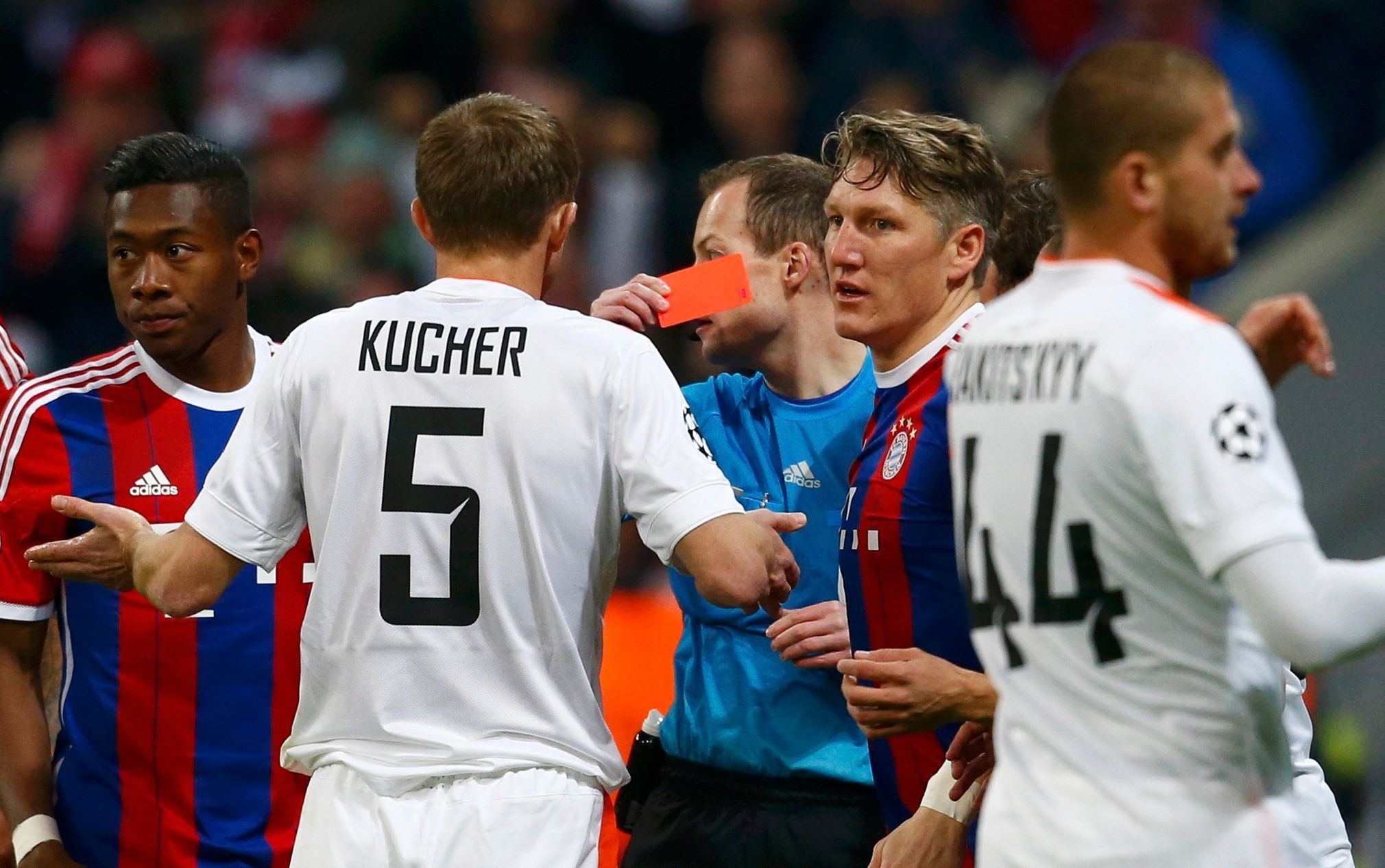 Match referee Collum shows a red card to Shakhtar Donetsk's Kucher as Bayern Munich's Aalaba and Schweinsteiger watch during their Champions League Round of 16 second leg soccer match in Munich