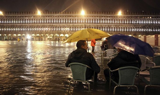 People sit on chairs in a flooded St Mark's Square at night during a period of seasonal high water in Venice November 1, 2012. The water level in the canal city rose to 140 cm (55 inches) above normal, according to the monitoring institute. REUTERS/Manuel Silvestri (ITALY - Tags: ENVIRONMENT SOCIETY TRAVEL DISASTER) Published: Lis. 1, 2012, 8:05 dop.