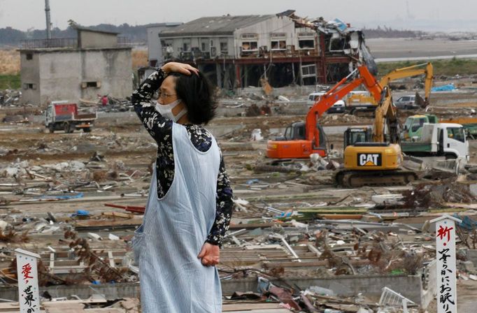 Žena sleduje odklízení trosek v poničeném městě Natori. Snímek z června 2011. Zemětřesení a následná tsunami Japonsko zasáhly 11. března.