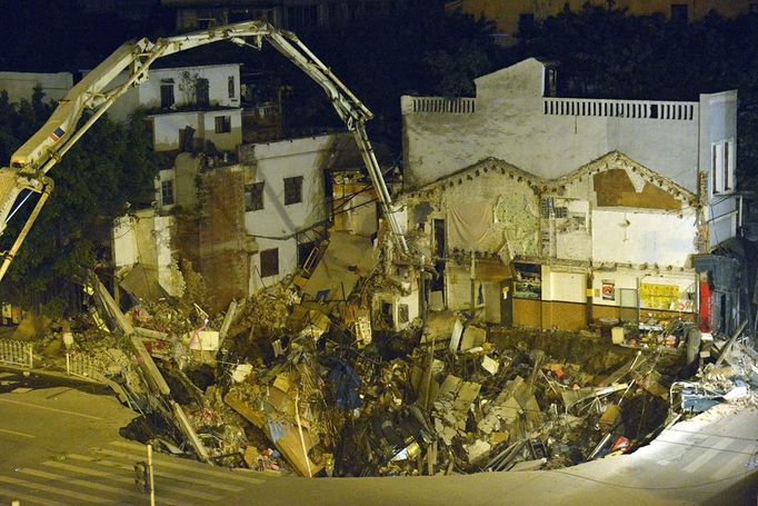 This picture taken on January 28, 2013 shows workers using machinery to fill in a sinkhole that buildings collapsed into near a subway construction site in Guangzhou, south China's Guangdong province. The hole measured about 1,000 square feet across and was around 30 feet deep, but no one was killed, according to a state media report. CHINA OUT AFP PHOTO