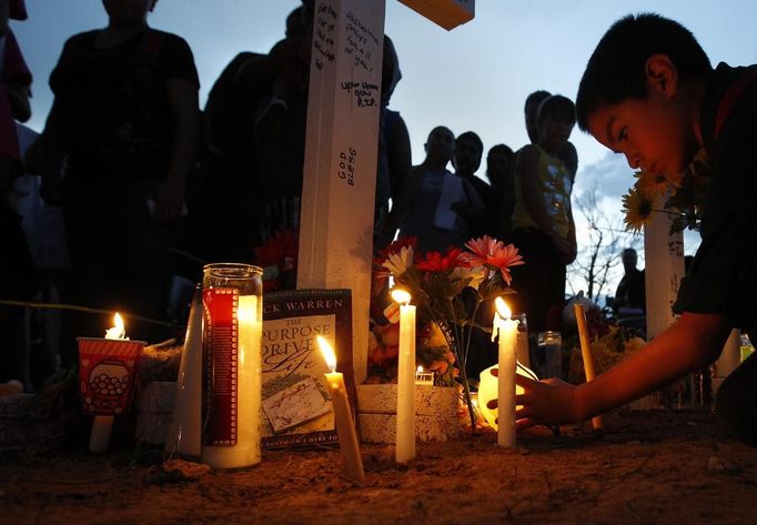 A boy lights a candle at a memorial for victims behind the theater where a gunman opened fire last Friday on moviegoers in Aurora, Colorado July 22, 2012. President Barack Obama travelled to Colorado on Sunday to meet families bereaved after a gunman went on a shooting rampage at a movie theater in a Denver suburb, killing at least 12 people and wounding 58. REUTERS/Shannon Stapleton (UNITED STATES - Tags: CRIME LAW CIVIL UNREST OBITUARY TPX IMAGES OF THE DAY) Published: Čec. 23, 2012, 3:22 dop.