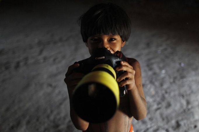 A Yawalapiti boy poses with a camera in the Xingu National Park, Mato Grosso State, May 8, 2012. In August the Yawalapiti tribe will hold the Quarup, which is a ritual held over several days to honour in death a person of great importance to them. This year the Quarup will be honouring two people - a Yawalapiti Indian who they consider a great leader, and Darcy Ribeiro, a well-known author, anthropologist and politician known for focusing on the relationship between native peoples and education in Brazil. Picture taken May 8, 2012. REUTERS/Ueslei Marcelino (BRAZIL - Tags: SOCIETY ENVIRONMENT) ATTENTION EDITORS - PICTURE 22 OF 28 FOR PACKAGE 'LIFE WITH THE YAWALAPITI TRIBE' Published: Kvě. 15, 2012, 5:11 odp.