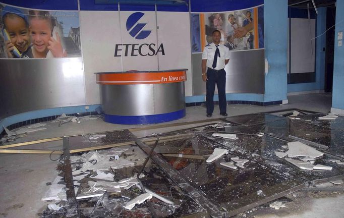 A security guard stands inside a damaged office of Cuban national telecommunications company ETECSA, after Hurricane Sandy hit Santiago de Cuba October 25, 2012. Strengthening rapidly after tearing into Jamaica and crossing the warm Caribbean Sea, Sandy hit southeastern Cuba early on Thursday with 105-mph winds that cut power and blew over trees across the city of Santiago de Cuba. Reports from the city of 500,000 people, about 470 miles (750 km) southeast of Havana spoke of significant damage, with many homes damaged or destroyed. REUTERS/Miguel Rubiera/Cuban Government National Information Agency-AIN/Handout (CUBA - Tags: ENVIRONMENT DISASTER BUSINESS TELECOMS) FOR EDITORIAL USE ONLY. NOT FOR SALE FOR MARKETING OR ADVERTISING CAMPAIGNS. THIS IMAGE HAS BEEN SUPPLIED BY A THIRD PARTY. IT IS DISTRIBUTED, EXACTLY AS RECEIVED BY REUTERS, AS A SERVICE TO CLIENTS Published: Říj. 25, 2012, 7:37 odp.