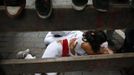 Revellers embrace on the ground as other revellers sit on the fence while they wait for the start of the fifth running of the bulls at the Estafeta corner during San Fermin festival in Pamplona July 11, 2012. Several runners suffered light injuries in a run that lasted three minutes and twelve seconds, according to local media. REUTERS/Susana Vera (SPAIN - Tags: SOCIETY) Published: Čec. 11, 2012, 9:25 dop.