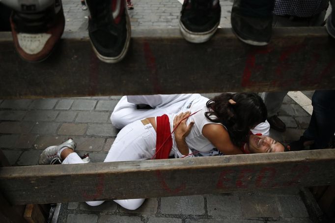 Revellers embrace on the ground as other revellers sit on the fence while they wait for the start of the fifth running of the bulls at the Estafeta corner during San Fermin festival in Pamplona July 11, 2012. Several runners suffered light injuries in a run that lasted three minutes and twelve seconds, according to local media. REUTERS/Susana Vera (SPAIN - Tags: SOCIETY) Published: Čec. 11, 2012, 9:25 dop.