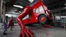 Workers check the function of the hydraulic arms of a London bus that is being transformed into a robotic sculpture by Czech artist David Cerny in Prague July 2, 2012. The bus, which Cerny hopes could become an unofficial mascot of the London 2012 Olympic Games, does push-ups with the help of an engine powering a pair of robotic arms, and the motion is accompanied by a recording of sounds evoking tough physical effort. It will be parked outside the Czech Olympic headquarters in London for the duration of the Games. Picture taken July 2, 2012. REUTERS/Petr Josek (CZECH REPUBLIC - Tags: ENTERTAINMENT SPORT OLYMPICS) Published: Čec. 22, 2012, 5:58 odp.