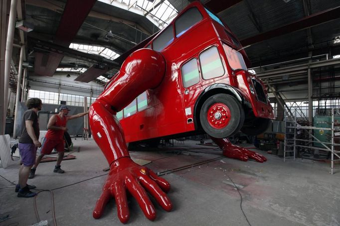 Workers check the function of the hydraulic arms of a London bus that is being transformed into a robotic sculpture by Czech artist David Cerny in Prague July 2, 2012. The bus, which Cerny hopes could become an unofficial mascot of the London 2012 Olympic Games, does push-ups with the help of an engine powering a pair of robotic arms, and the motion is accompanied by a recording of sounds evoking tough physical effort. It will be parked outside the Czech Olympic headquarters in London for the duration of the Games. Picture taken July 2, 2012. REUTERS/Petr Josek (CZECH REPUBLIC - Tags: ENTERTAINMENT SPORT OLYMPICS) Published: Čec. 22, 2012, 5:58 odp.