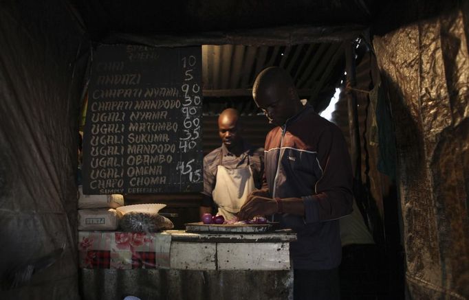 Denis Onyango Olang, (R), a 26 year-old assistant cook, prepares food in a dimly lit kitchen at a hotel in Nairobi's Kibera slum in the Kenyan capital April 30, 2012. Onyango Olang studied statistics and chemistry at Jomo Kenyatta University of Agriculture and Technology where he received a degree in science. He has been searching for permanent employment for two years but has decided to make a living working in the slums for the last eight months.