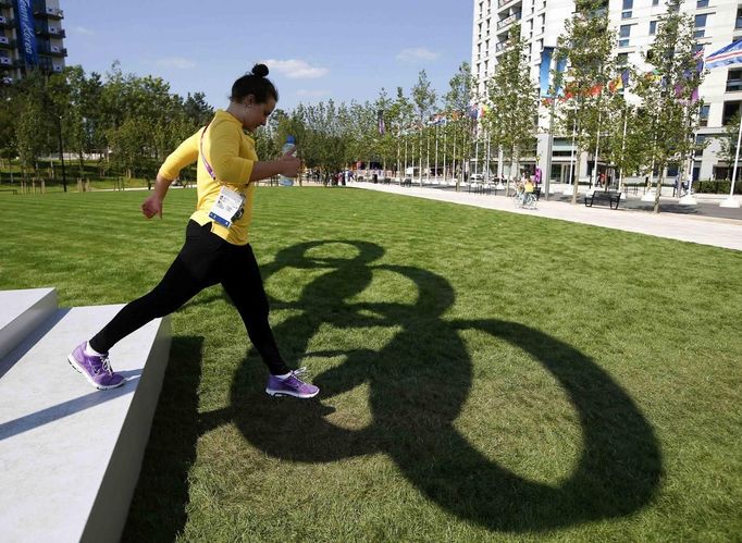 Yolane Kukla, a swimmer from Australia, walks off the steps into the shadows of the Olympic rings at the Athletes' Village at the Olympic Park, July 22, 2012. Opening ceremonies for the London 2012 Olympics will be held on Friday. REUTERS/Jae C. Hong/Pool (BRITAIN - Tags: SPORT OLYMPICS SPORT SWIMMING) Published: Čec. 22, 2012, 4:22 odp.