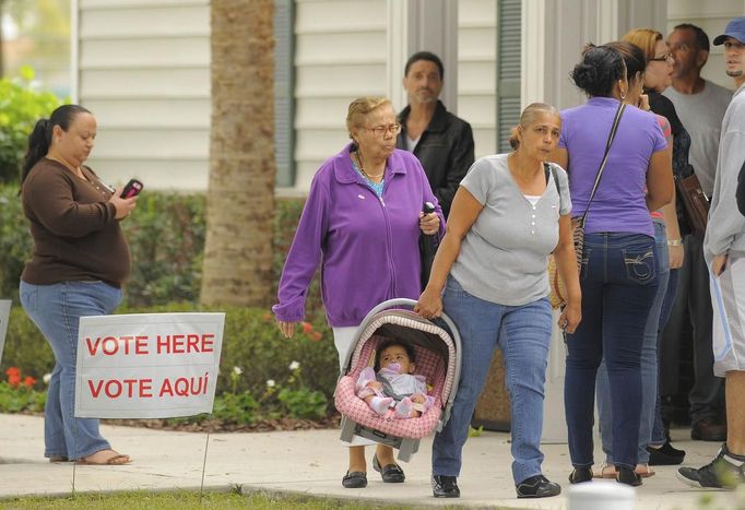 Volby, nevolby - péči o děti nelze ošidit. Záběr na ženu nesoucí malé dítě ve frontě lidí čekající u volebního okrsku v Kissimmee. Florida