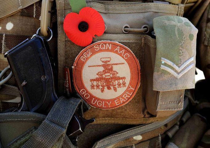 Corporal Graham Carr, arming loading point commander (ALPC) of 662 Squadron, 3 Regiment Army Air Corps, wears a poppy next to his weapon, and badge on his body armour, at Camp Bastion, southern Afghanistan in this photograph taken on November 1, 2012, and released on January 21, 2013. Britain's Prince Harry, who is serving as a pilot/gunner with 662 Squadron Army Air Corps, is on a posting to Afghanistan that runs from September 2012 to January 2013. Photograph taken November 1, 2012. REUTERS/John Stillwell/Pool (AFGHANISTAN - Tags: MILITARY POLITICS SOCIETY ROYALS CONFLICT) Published: Led. 21, 2013, 7:34 odp.