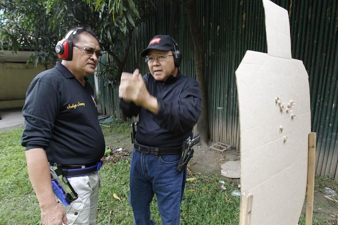 Jaime "Jimmy" Santiago (L), a lower court judge in Manila, talks to his fellow court judge Armando Yanga while checking a target cardboard during their shooting practice at a police firing range in Manila March 6, 2013. Santiago, a former police officer who headed a special weapons and tactics (SWAT) unit, favours arming Filipino judges to protect themselves from disgruntled litigants who can't accept decisions and criminal syndicates whose members were sent to jail. There had been cases of shootings inside courtrooms. Picture taken March 6, 2013. REUTERS/Romeo Ranoco (PHILIPPINES - Tags: POLITICS CRIME LAW) Published: Dub. 4, 2013, 11:20 dop.