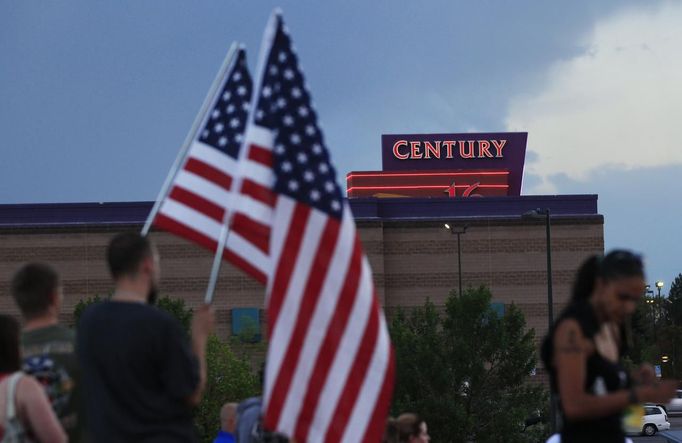 People stand on a hillside behind a memorial for victims behind the theater where a gunman opened fire last Friday on moviegoers in Aurora, Colorado July 22, 2012. President Barack Obama travelled to Colorado on Sunday to meet families bereaved after a "demonic" gunman went on a shooting rampage at a movie theater in a Denver suburb, killing at least 12 people and wounding 58. REUTERS/Shannon Stapleton (UNITED STATES - Tags: CRIME LAW CIVIL UNREST OBITUARY) Published: Čec. 23, 2012, 3:21 dop.