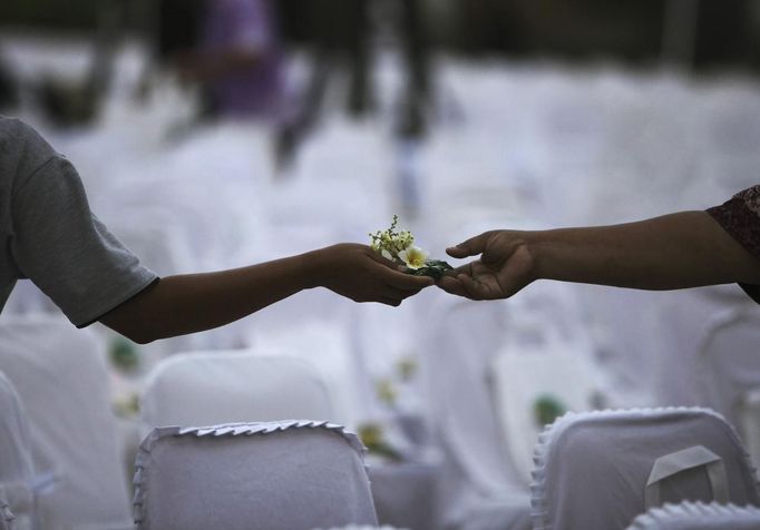 A flower is exchanged between friends during a commemoration service for the 10th anniversary of the Bali bombing in Garuda Wisnu Kencana (GWK) cultural park in Jimbaran, Bali October 12, 2012. Eighty-eight Australians were among the 202 people killed in the attacks on the Sari Club and Paddy's Bar at the popular tourist area of Kuta on October 12, 2002. REUTERS/Beawiharta (INDONESIA - Tags: ANNIVERSARY POLITICS) Published: Říj. 12, 2012, 5:32 dop.