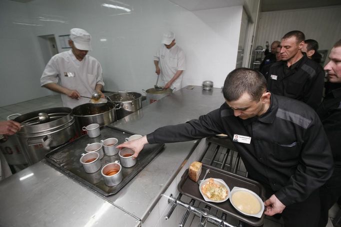 An inmate receives a portion of food while others stand in line at a high-security male prison camp outside Russia's Siberian city of Krasnoyarsk May 14, 2013. High-security male prison camp number 17 is intended to house male inmates who are serving a sentence for the first time, and have been convicted for serious crimes. Prisoners at the facility work in wood and metal processing shops, manufacture furniture, sew clothes and do other kinds of work. They can also take part in educational, sport and cultural programs. Picture taken May 14, 2013. REUTERS/Ilya Naymushin (RUSSIA - Tags: CRIME LAW SOCIETY) ATTENTION EDITORS: PICTURE 18 OF 29 FOR PACKAGE 'INSIDE SIBERIA'S PRISONS' SEARCH 'ILYA PRISON' FOR ALL IMAGES Published: Čer. 19, 2013, 10:04 dop.