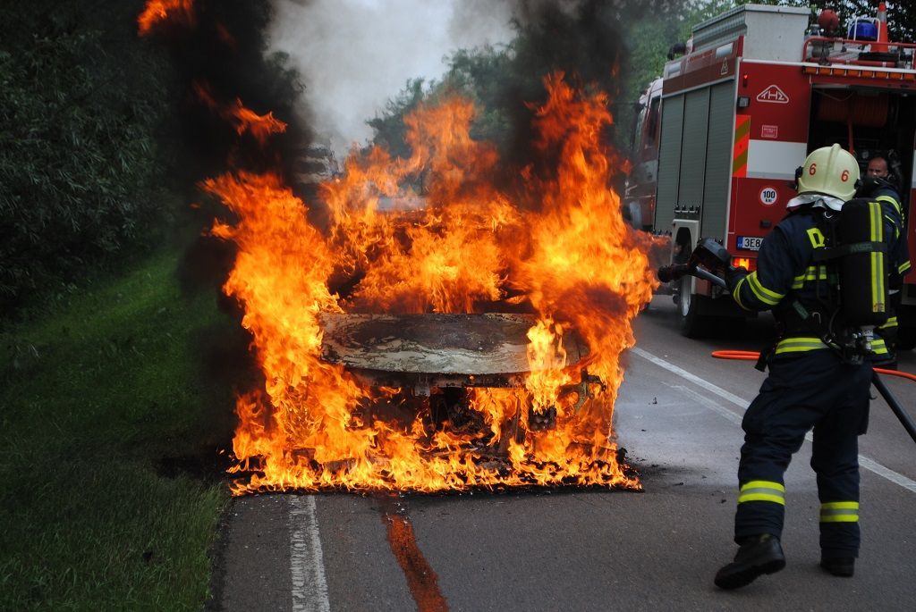 Hasiči se snaží uhasit hořící auto, plameny šlehají vysoko
