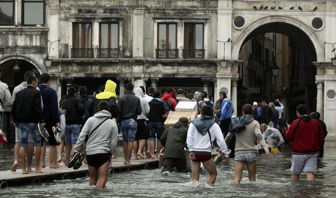 Tourists walk on raised platforms for flood waters in St. Mark Square during a period of seasonal high water in Venice October 27, 2012. The water level in the canal city rose to 127 cm (50 inches) above the normal level, according to the monitoring institute. REUTERS/Manuel Silvestri (ITALY - Tags: ENVIRONMENT SOCIETY TRAVEL) Published: Říj. 27, 2012, 12:33 odp.