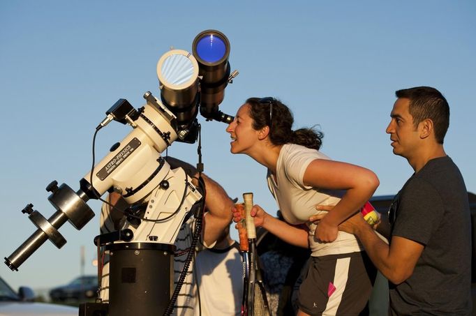 Anita Sokal-Davidson (L) of Rochester, New York, is helped by Tim Stevens as she looks through a telescope from Cobbs Hill Reservoir as the planet Venus transits across the sun over Rochester, New York, June 5, 2012. The planet Venus made a slow transit across the face of the sun on Tuesday, the last such passing that will be visible from Earth for 105 years. REUTERS/Adam Fenster (UNITED STATES - Tags: ENVIRONMENT SCIENCE TECHNOLOGY) Published: Čer. 6, 2012, 3:32 dop.