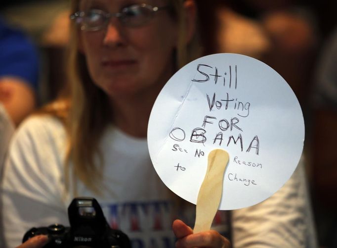 A woman in the audience holds a handwritten sign reading "Still Voting for Obama, See No Reason to Change" at a campaign rally with Republican presidential nominee Mitt Romney in Apopka, Florida October 6, 2012. REUTERS/Brian Snyder (UNITED STATES - Tags: POLITICS ELECTIONS USA PRESIDENTIAL ELECTION) Published: Říj. 7, 2012, 12:29 dop.