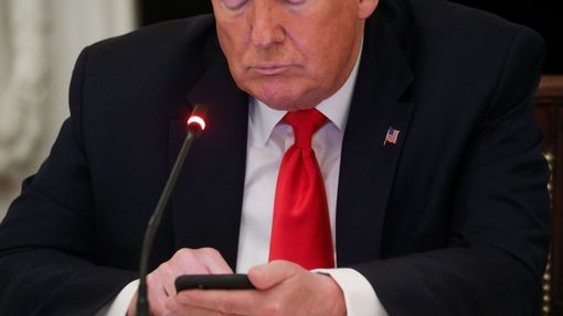 Americký prezident Donald Trump na mobilu.