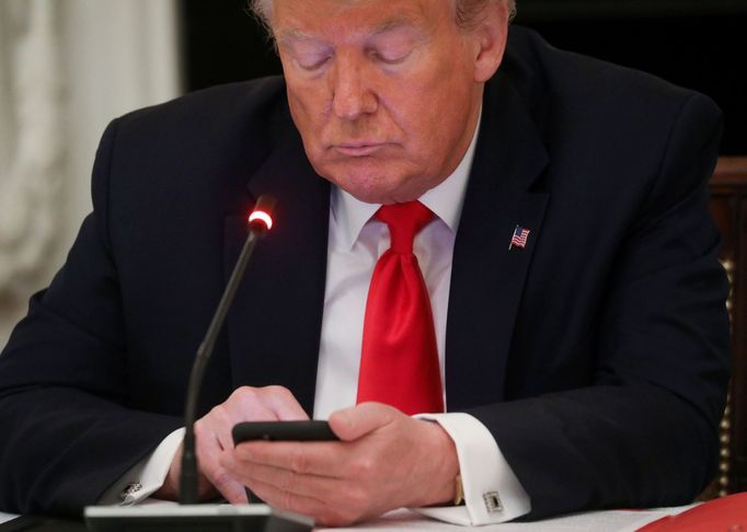 Americký prezident Donald Trump na mobilu.