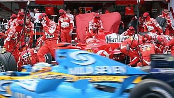 Fernando Alonso s Renaultem (vpředu) projíždí kolem boxů Ferrari svého rivala v boji o titul Michaela Schumachera.