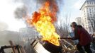 An anti-government protester moves a burning tyre at a barricade in Kiev February 21, 2014.