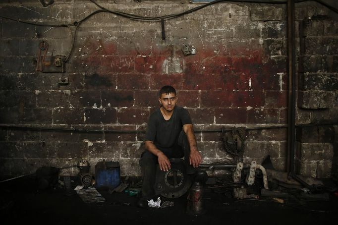 Palestinian Shadi Yassin, 17, poses for a photograph in a car repair garage in Gaza City May 30, 2013. Yassin left school to work as an apprentice in the garage so that he could support his family's income. Apprentice mechanics earn around $100 per month, garage owners saidowners said. REUTERS/Mohammed Salem (GAZA - Tags: TRANSPORT SOCIETY EMPLOYMENT PORTRAIT) Published: Kvě. 30, 2013, 12:55 odp.