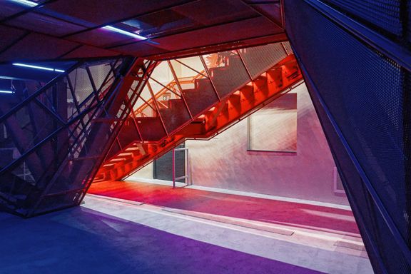Světla a červená schodiště vytváří pod masivní konstrukcí zajímavou hru barev.
