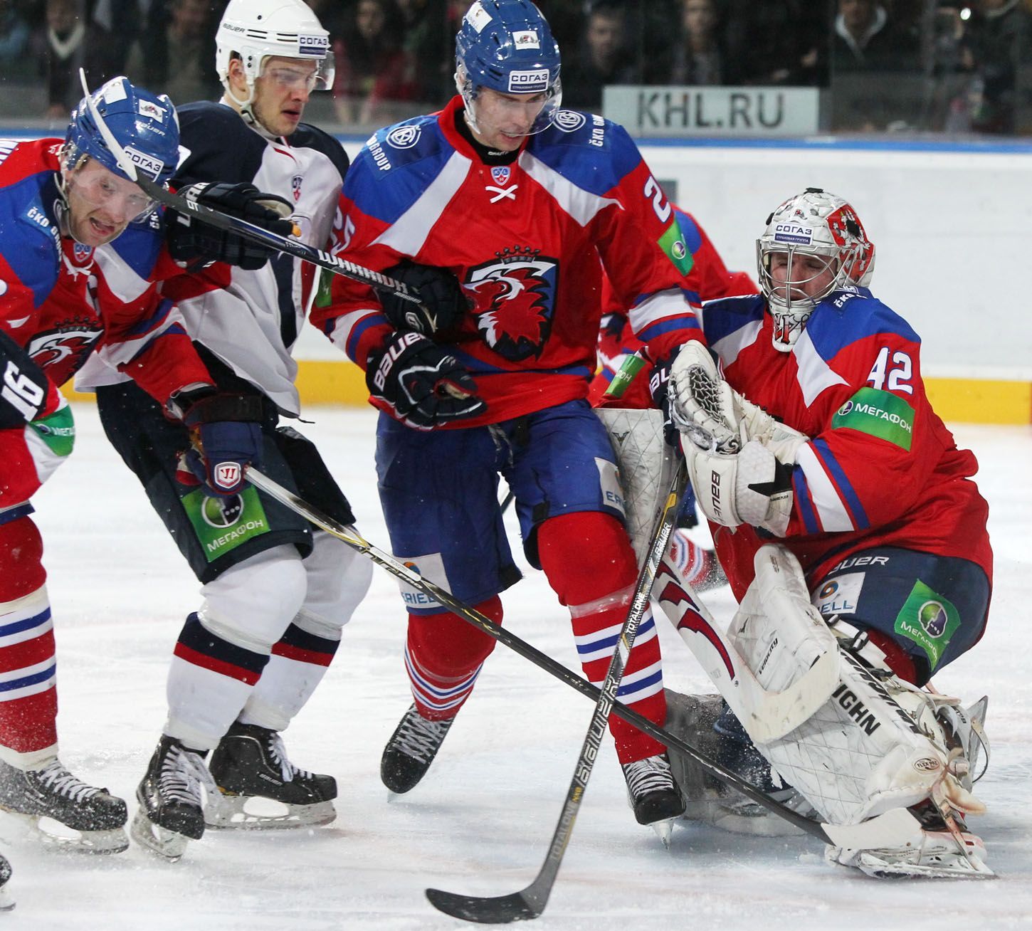 Hokejista Lva Praha Mathias Porseland a brankář Tomáš Pöpperle brání protihráče v utkání KHL 2012/13 proti Slovanu Bratislava.