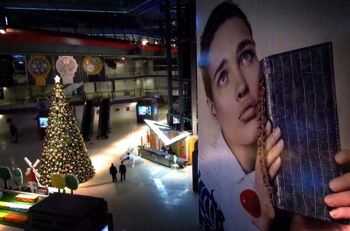 Two men walk through a newly built shopping mall, which includes a Christmas tree in the main forecourt, in central Beijing November 27, 2012. Picture taken November 27, 2012. REUTERS/David Gray (CHINA - Tags: BUSINESS EMPLOYMENT) Published: Lis. 28, 2012, 3:38 dop.