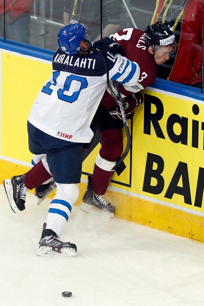 Latvia's Juris Stals (R) is pinned to the boards by Finland's Jere Karalahti (L) during the second period of their men's ice hockey World Championship group B game at Min