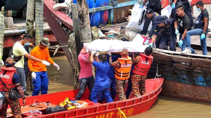 Malajsijští záchranáři vynášejí na pevninu těla obětí lodního neštěstí.